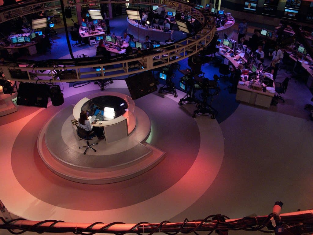 Elevated view of a modern television newsroom with editors at workstations