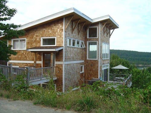 Exterior of a modern wood-shingled house with large windows and a deck
